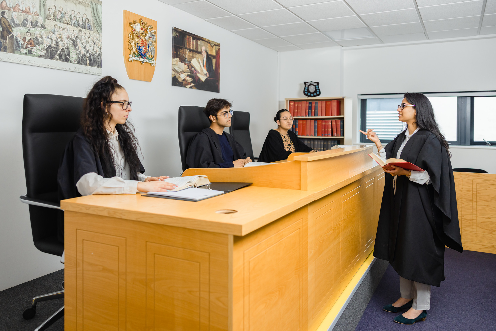 Image of a mock courtroom used by the School of Law, occupied by four students using the room's purpose-built legal equipment