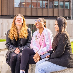 Three students sat in courtyard