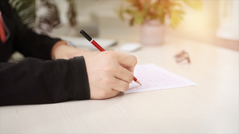 close up of a hand holding a pencil writing on some white paper