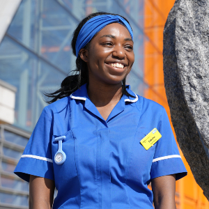 Photograph of Sabrina Ffrench in medical clothing standing in front of a sculpted heart