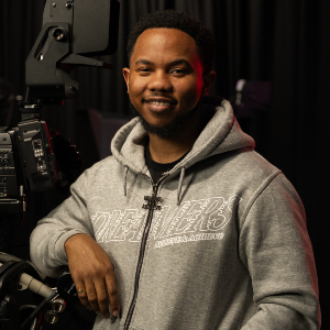Photograph of Theo Johnson with a film camera on a darkened set