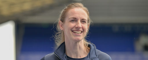 Kerys Harrop in a sports stadium holding a football under her arm
