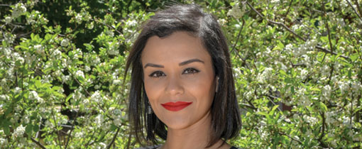 Nathalie Flores standing next to a tree, wearing a black blazer with a multicoloured brooch