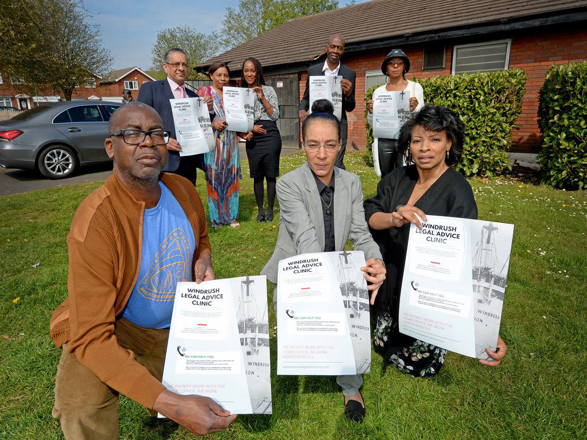 A group of people holding posters for the Windrush Legal Advice Centre