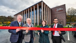 Photograph of four people in work clothes cutting the red ribbon in front of the Cyber Quarter.