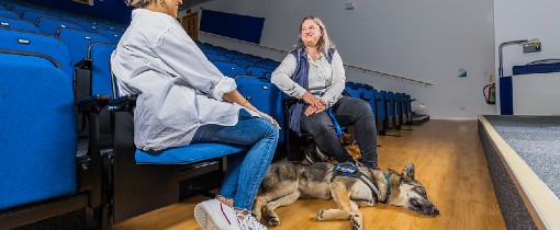 Person sat in lecture theatre with a service dog