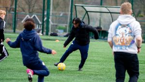 Students kicking football on football pitch