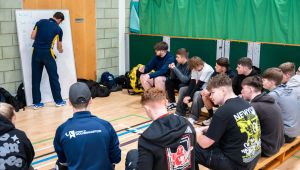 Lecturer writing on board with students sitting on bench and learning