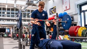 Male student holding weights above another student