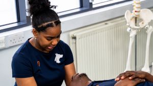 Female student checking male student's head while he's lying down