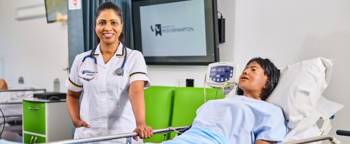 Female student next to dummy smiling at camera