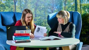 Academic and student sitting at table reading a book