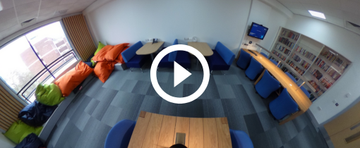 a room with bean bags, chairs and tables and a book case