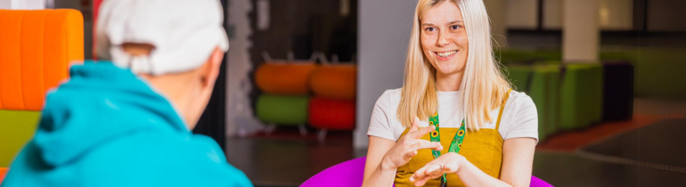 a female student smiles and signs to another person