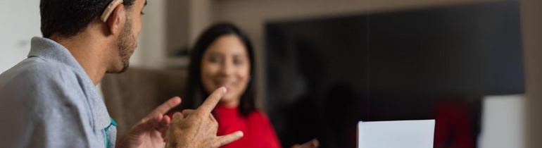 a man signs to a woman who smiles