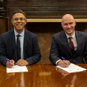 two men sign a contact and smile