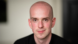 Andrew McMillan looking towards the camera in front of an open doorframe
