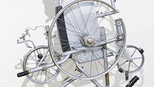 Artwork representing disabled experiences, wheels of various sizes assembled on a tangled metal frame