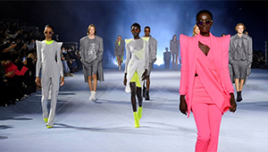 A crowd of models on a fashion runway displaying various outfits