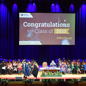 Photo of a graduation ceremony with a screen reading CONGRATULATIONS
