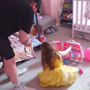 Photograph of James Gurdin and his young daughter playing with a dollhouse