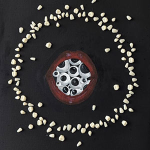 Painting of a pair of lips opening to a mouthful of eyes, surrounded by a circle of stones on a black background.