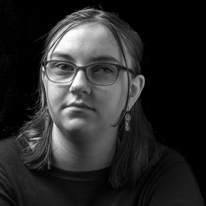Black and white portrait photograph of a young woman wearing glasses.