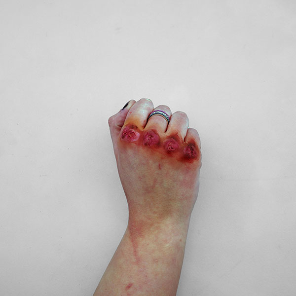 Photograph of a hand made up to resemble bloodied knuckles.