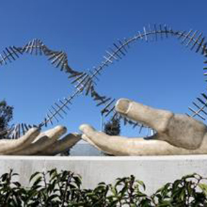2 large stone cared hands with a double helix of wire looped and intersecting each hand.