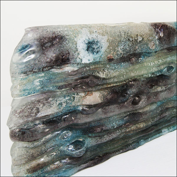 close up image of an abstract glass sculpture with white, green and purple shades