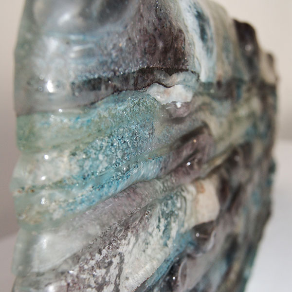 close up image of an abstract glass sculpture with white, green and purple shades