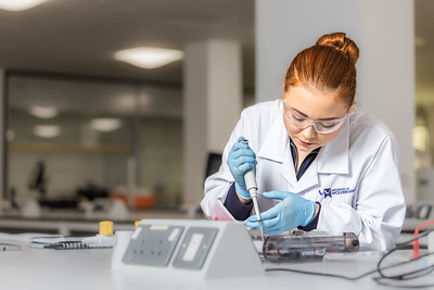 A student in a lab coat using scientific equipment