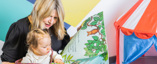A person showing a young child a picture book.