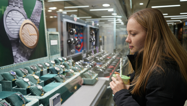 A student inspecting a window display of watches for sale