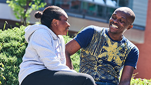 Students sitting in the courtyard on campus in the sunshine.