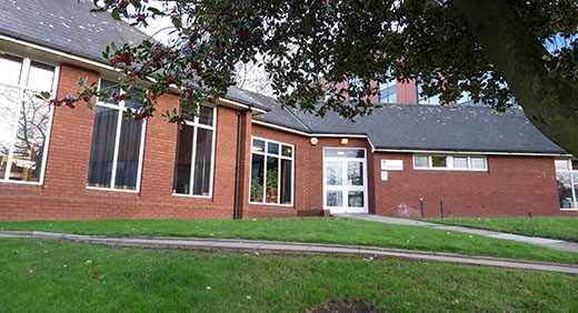 Photograph of the ML Chaplaincy building taken from outside, stone walking paths leading towards the single-floor red brick building.