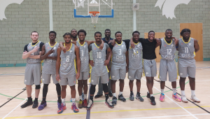The mens basketball team lined up in uniform inside the sports hall