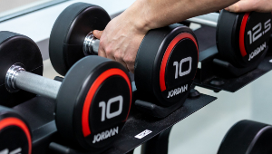 Photograph of a dumbbell weight rack, a pair of hands picking up two 10kg weights.
