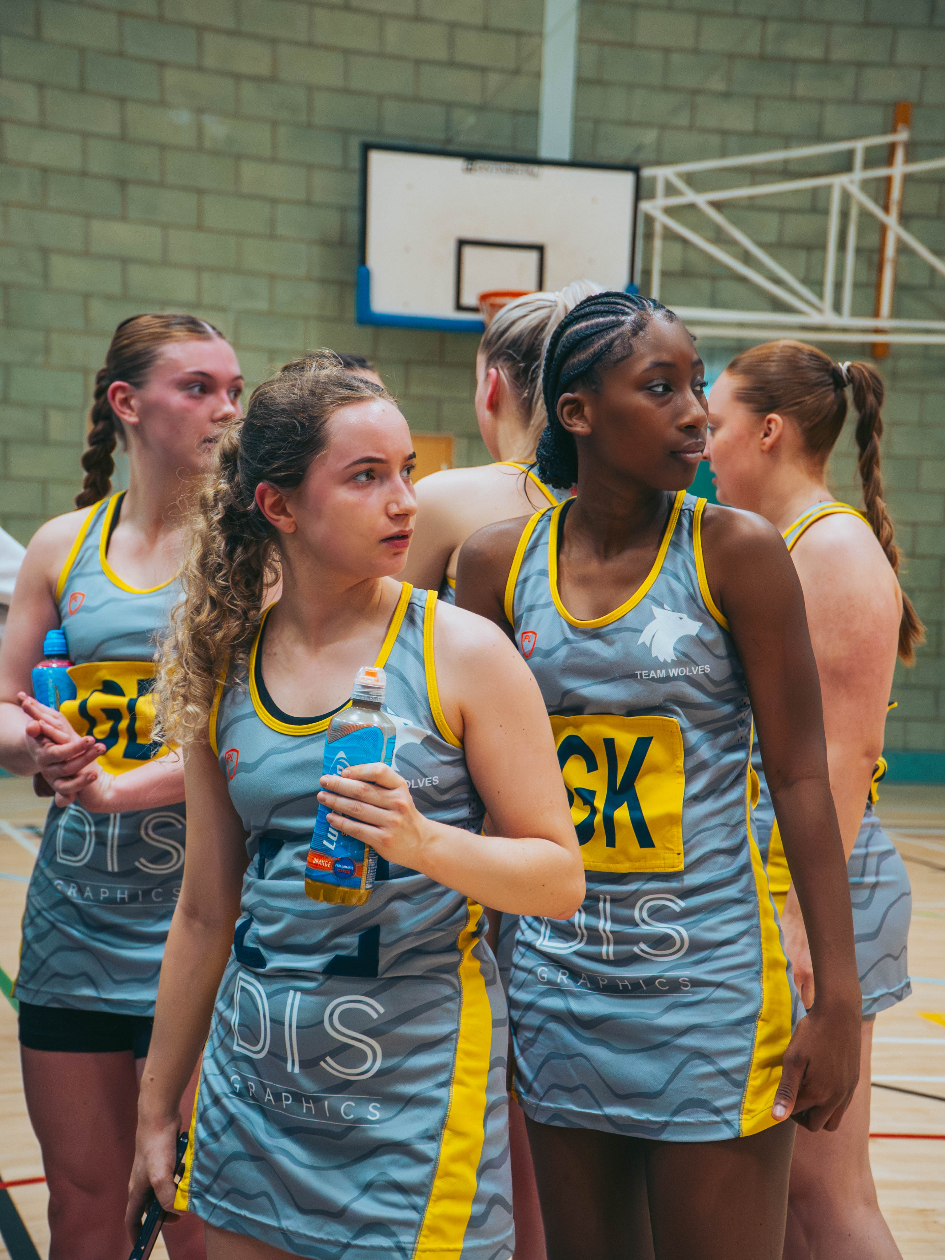Photograph of the University of Wolverhampton netball team on an indoor court, looking away from the camera and holding drink bottles.