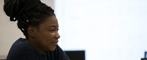 A student in class facing towards the lecturer, photographed adjacent to a window.