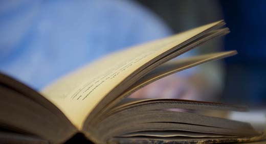 Image of a book being opened by a reader out of focus.