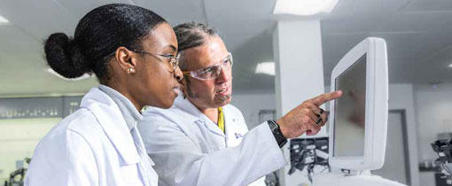 A biomedical science student looking at a sample on a monitor with her lecturer.