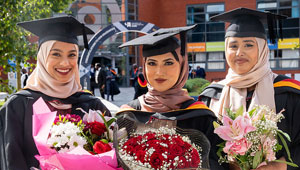 Three female students celebrating their graduation in the City Campus Courtyard